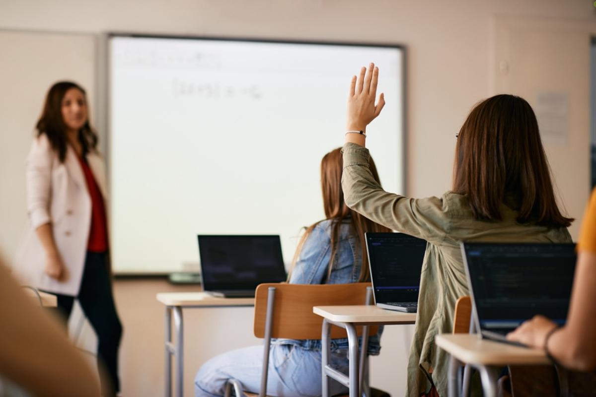 A photo of a person raising their hand in a classroom