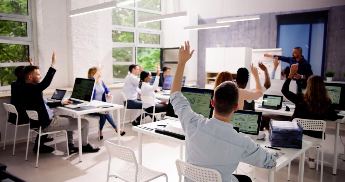 A picture of students raising their hands in a classroom