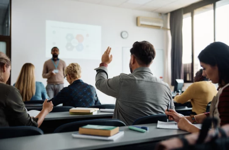 a person raising their hand in a classroom